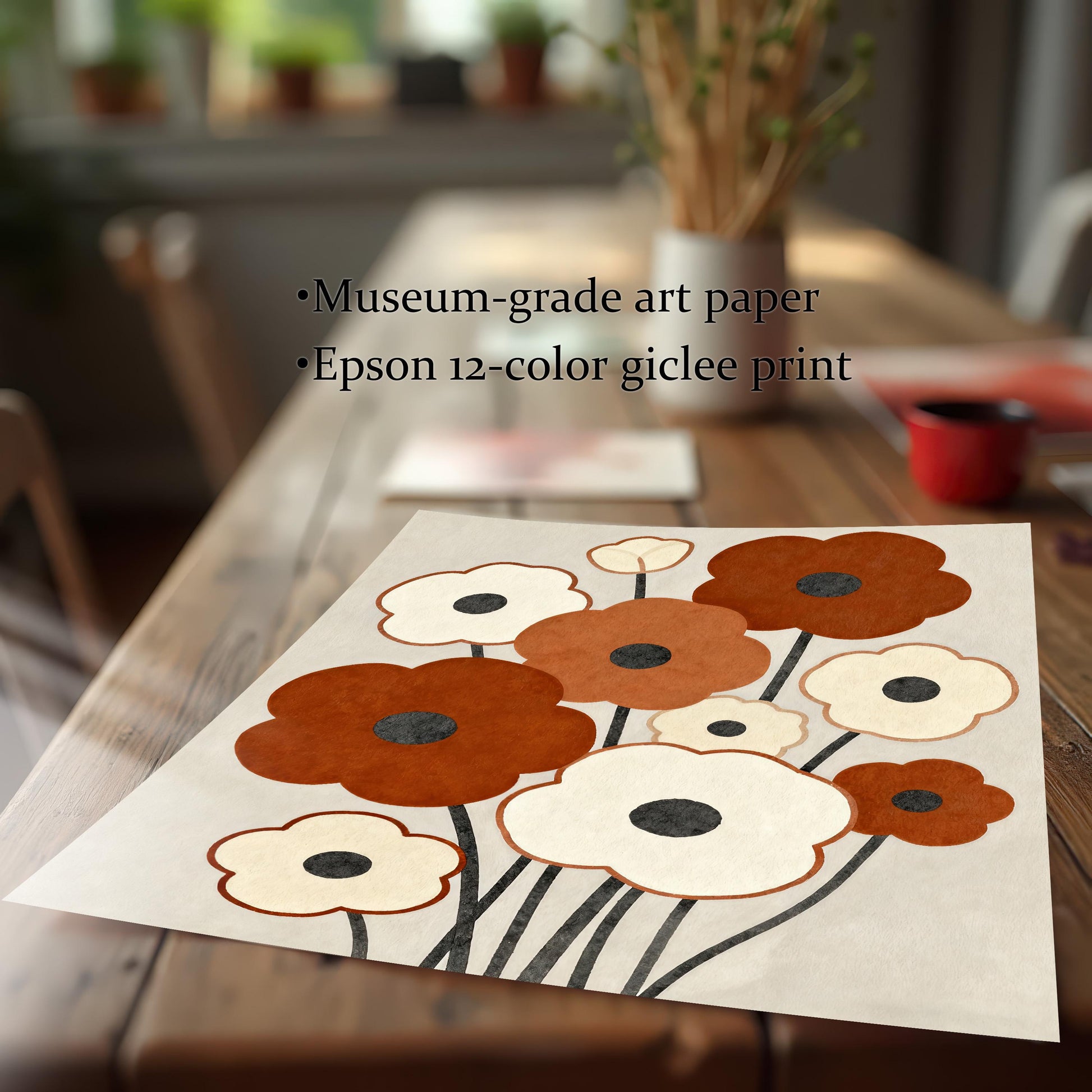A flat lay of an unframed abstract floral print with brown and white flowers sits on a long wooden dining table.