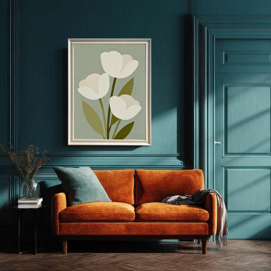 A framed art print of three white tulips hangs above an orange couch with a blue pillow and grey blanket. The wall and door are a deep blue color.