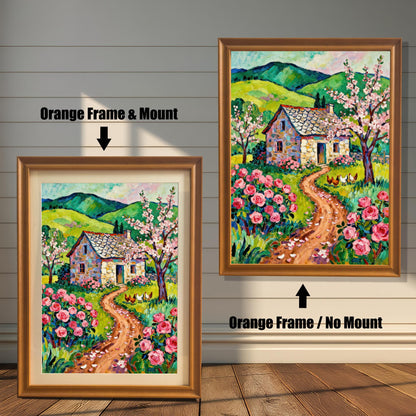 A side-by-side comparison of two orange-framed prints of a vibrant cottage painting. The smaller one on the left has a mount (matting), while the larger one on the right has no mount.