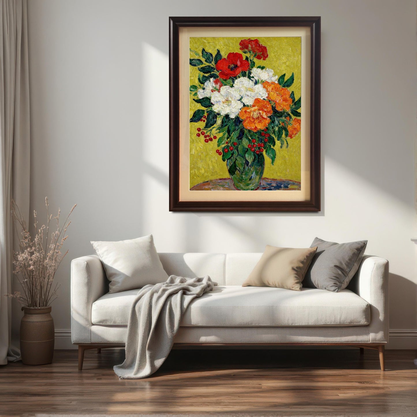 A framed painting of red, white, and orange flowers with a coffee-colored frame hanging on a wall above a white sofa with pillows and a throw blanket.