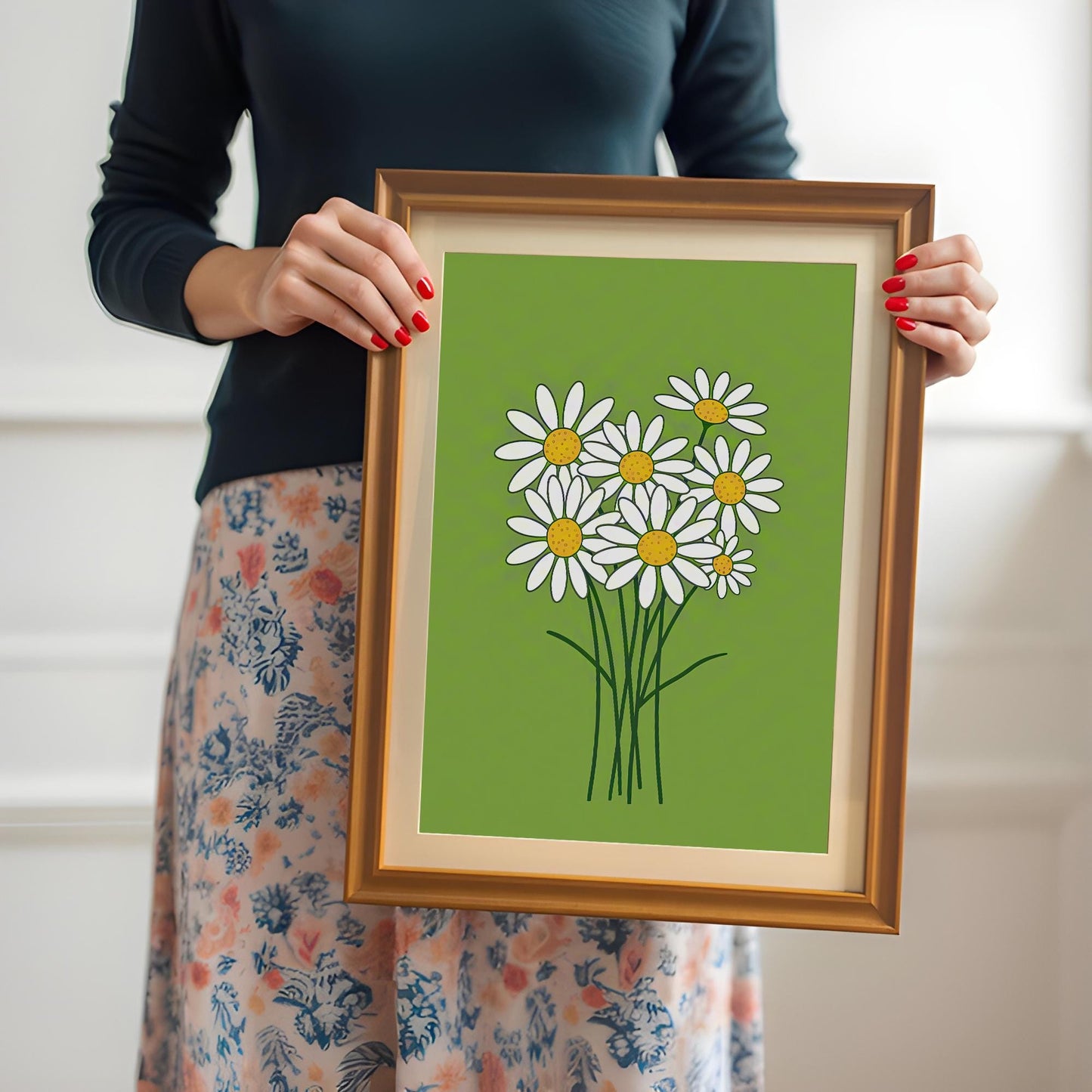 A person holds a framed print of a bunch of white daisies on a lime green background.