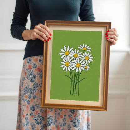 A person holds a framed print of a bunch of white daisies on a lime green background.