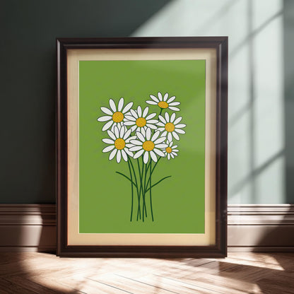 A framed print of a bunch of white daisies on a lime green background, leaning against a dark green wall in a sunlit room.