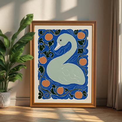 The framed swan print in a thick golden-brown wooden frame, leaning on a light hardwood floor next to a large potted green plant.