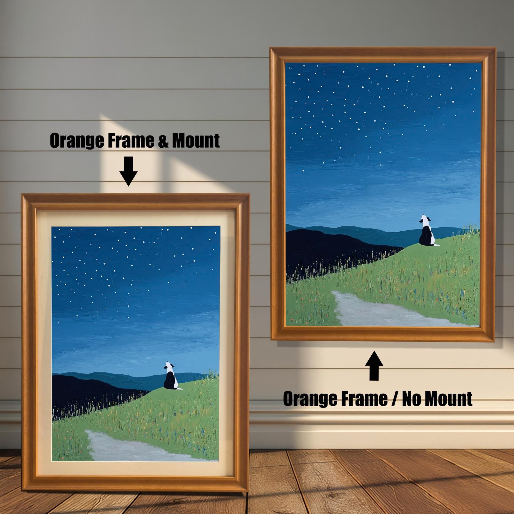 Stylized painting of a black and white dog sitting on a grassy hill under a starry night sky. The image shows two framed options: one on the left with an Orange Frame & Mount (matting), and one on the right with an Orange Frame / No Mount. Both are displayed against a white wood-paneled wall and a wooden floor.
