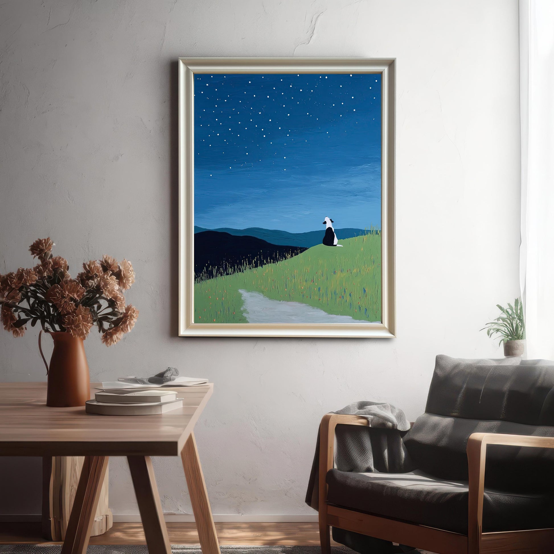 Framed starry night dog print in a Light Gold/Silver frame hanging on a gray textured wall above a wooden table and a dark leather armchair, in a brightly lit room.