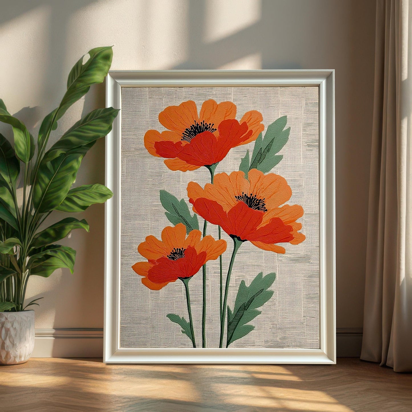 A framed print of three stylized orange poppies, framed in a White Frame, is leaning on a wood floor next to a potted green plant and neutral curtains. The print is framed with no mount.