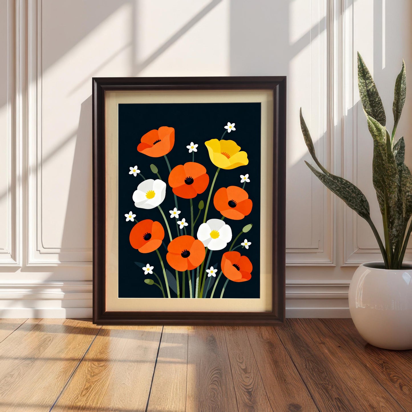 The poppy art print, set in a dark brown (coffee) frame with a light mat (mount), is leaning on a hardwood floor against a white wainscoted wall next to a potted snake plant.