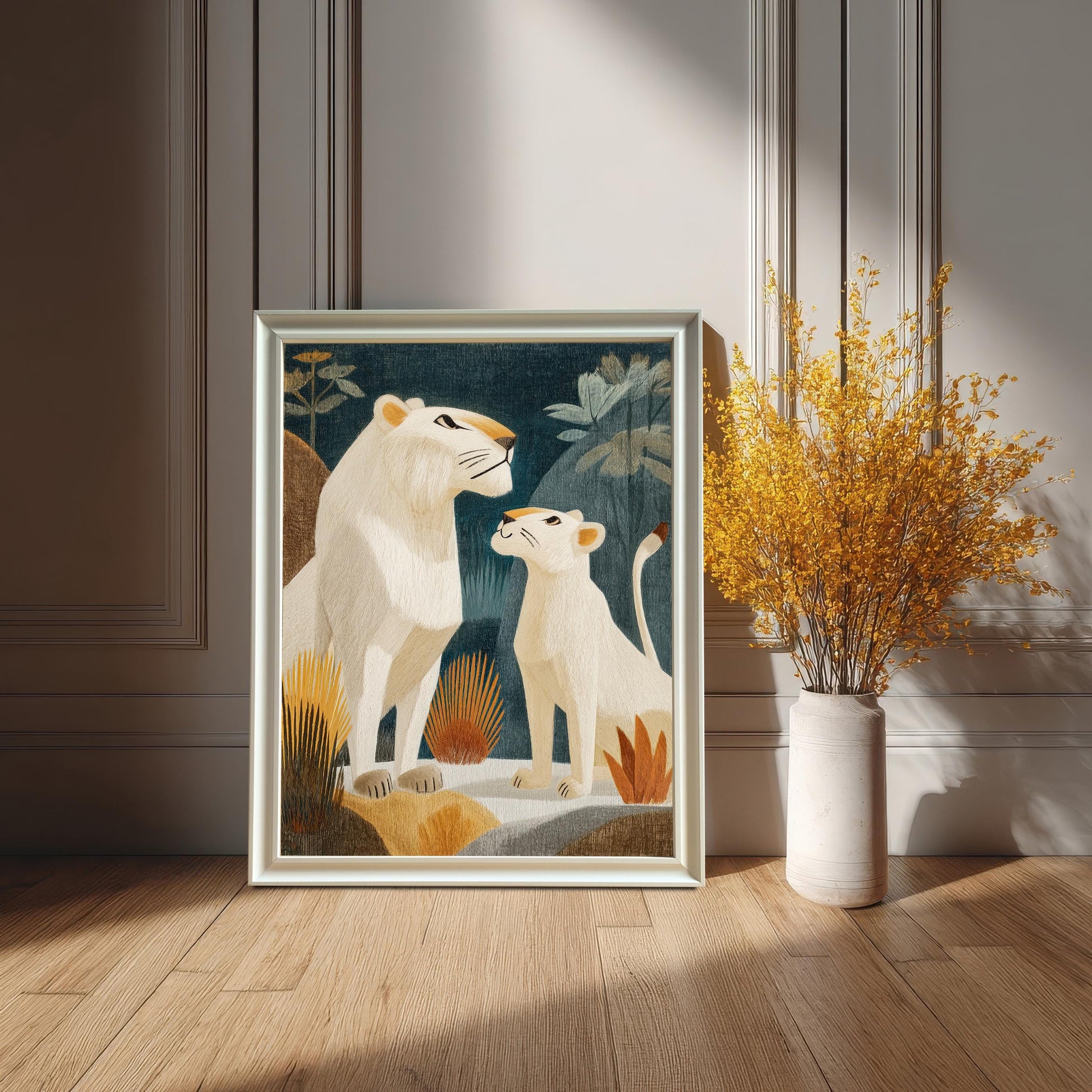 The framed print of a white lioness and cub, in a White frame with a mount, leaning on a wooden floor against a paneled wall. It sits next to a tall white vase holding a large bouquet of vibrant yellow dried flowers.