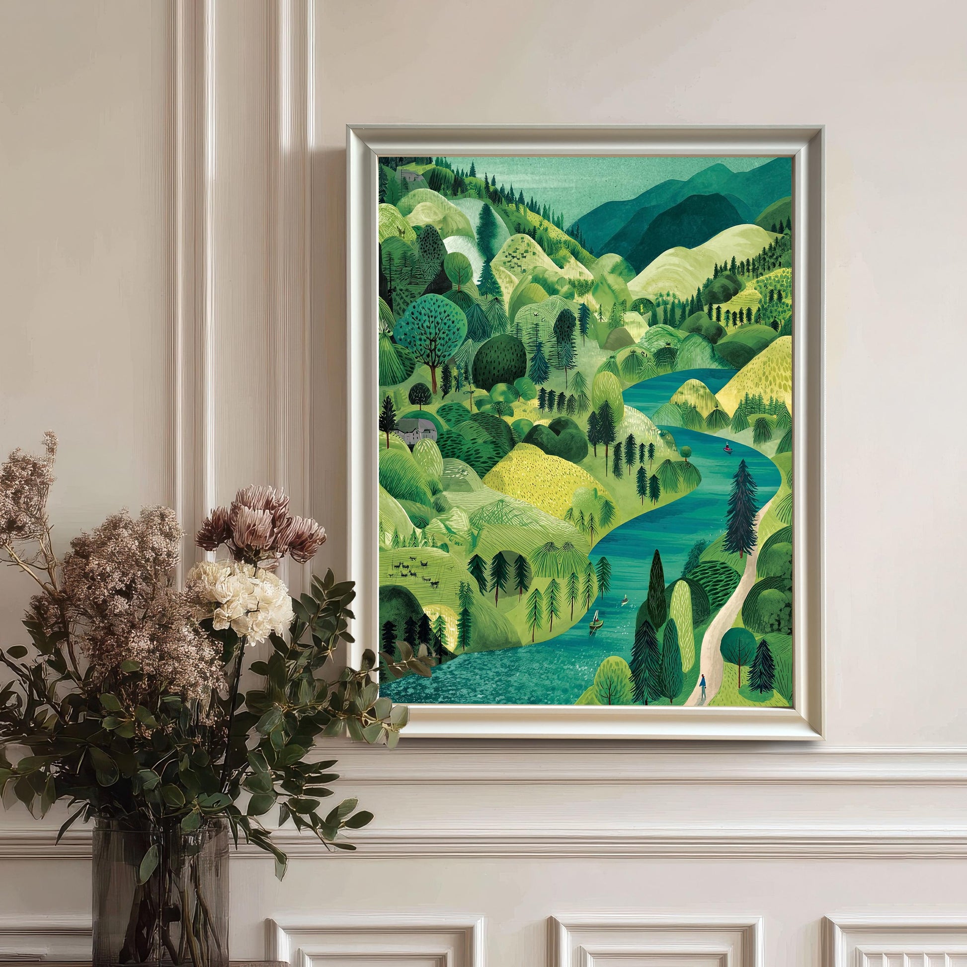 The framed landscape print in a White Frame hanging on a white wainscoted wall, next to a large vase of dried flowers and greenery.