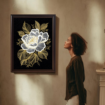 A woman with curly hair, wearing a striped shirt and light-colored pants, stands in profile admiring the black and gold floral print, which is framed in a dark Coffee Frame and hung on a textured beige wall.