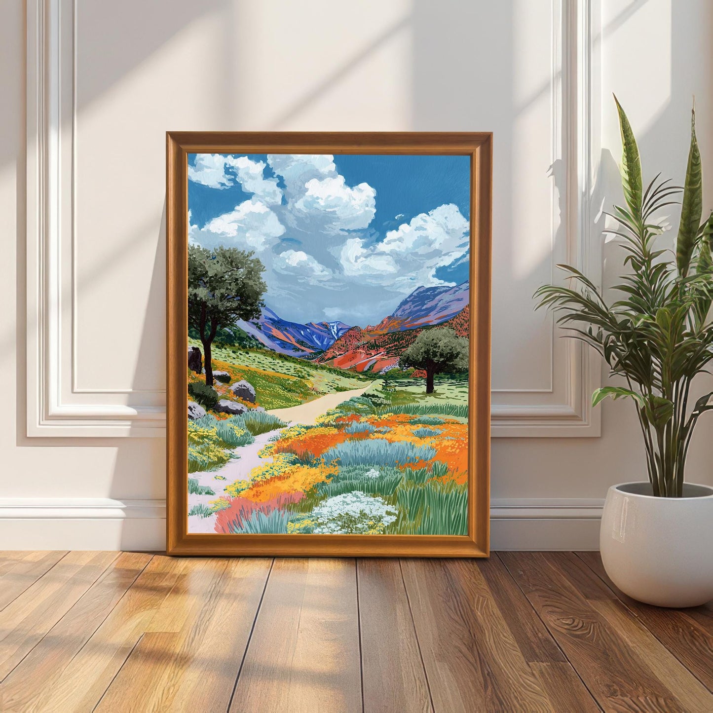 A colorful painting of a poppy and wildflower valley, framed in an Orange wood frame (no mount), leaning on a hardwood floor against a white paneled wall with a tall houseplant on the right.