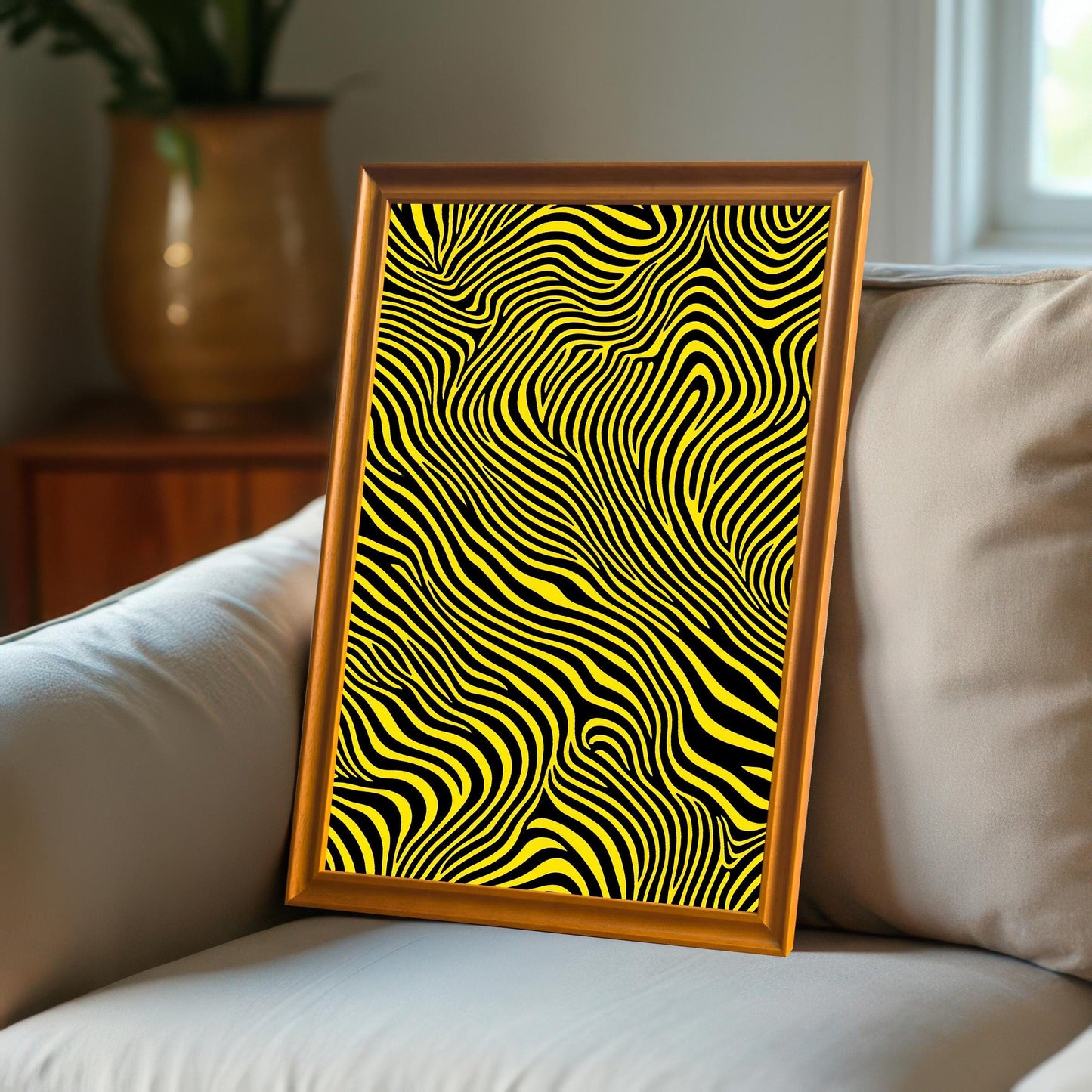 The abstract yellow and black striped print, framed in an Orange wood frame, leaning on the arm of a beige couch.