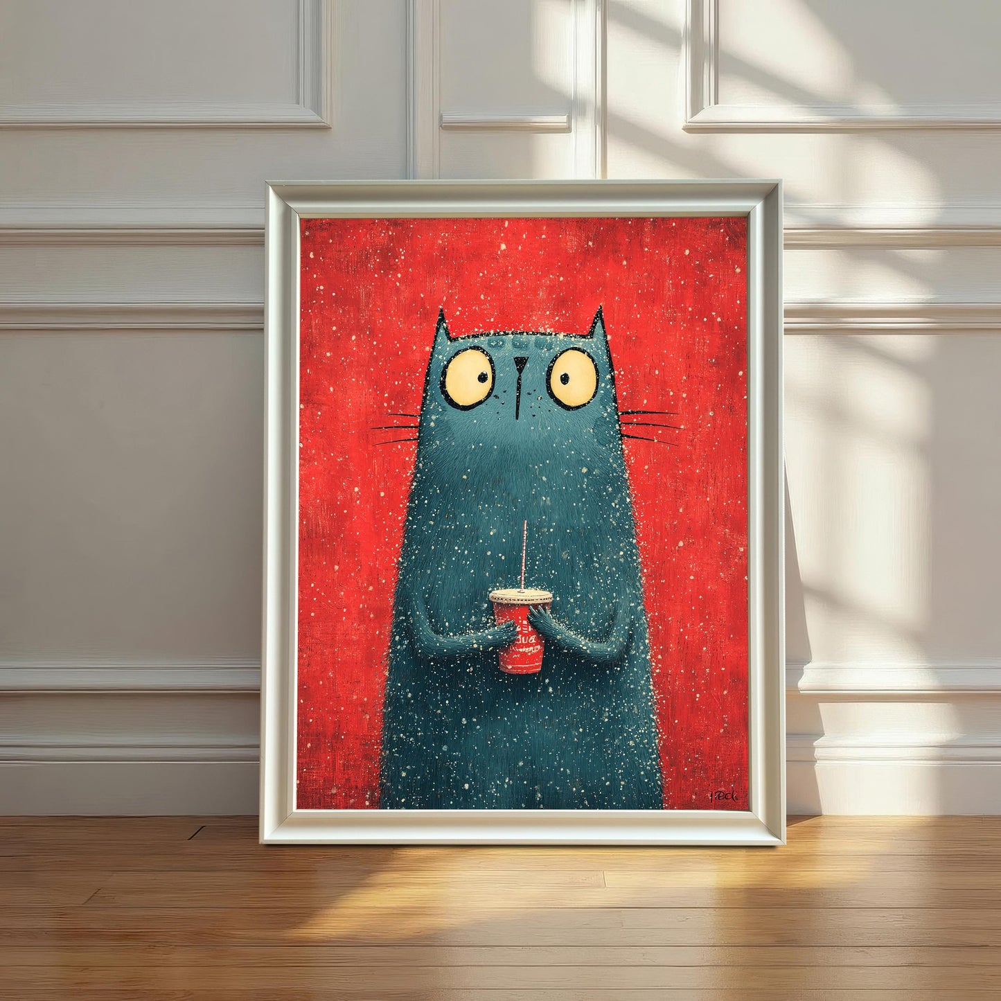 A framed art print featuring a stylized, fuzzy, blue-green cat holding a red cup against a red background. The print is in a White Frame and is leaning on a hardwood floor against a white, wainscoted wall.