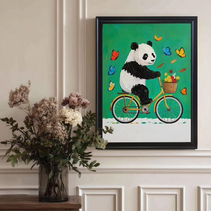 A framed art print of a panda on a bike hangs on a wall next to a large vase of dried flowers. The frame is black.