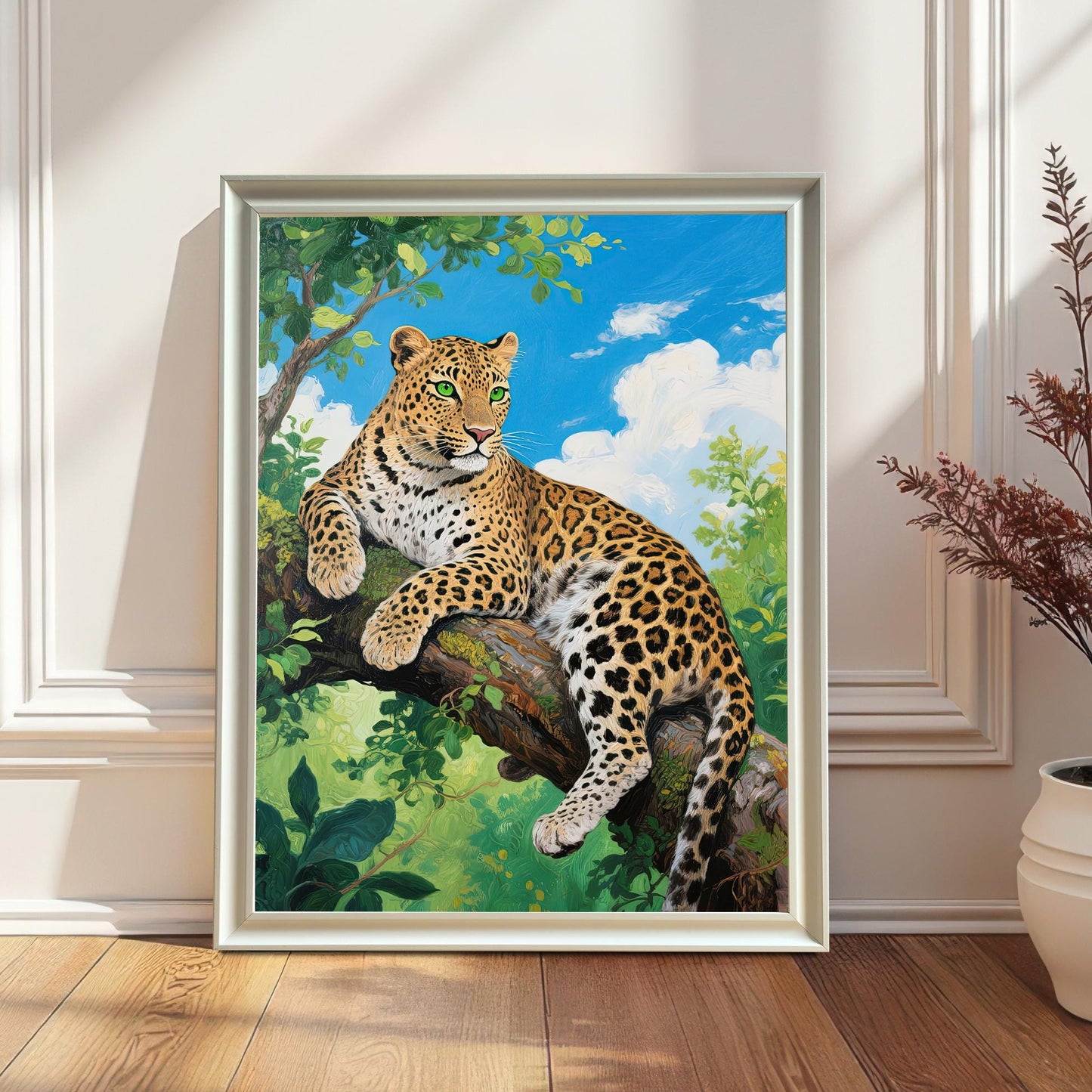 A white-framed painting of a leopard on a tree branch leans against a white wainscoting wall next to a tall, dried plant.