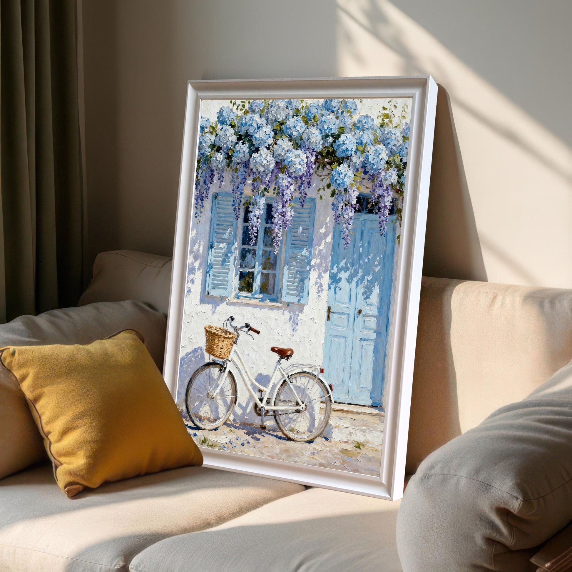 Framed print in a White frame leaning on a light-colored sofa next to a yellow pillow, showing sunlight and shadows.