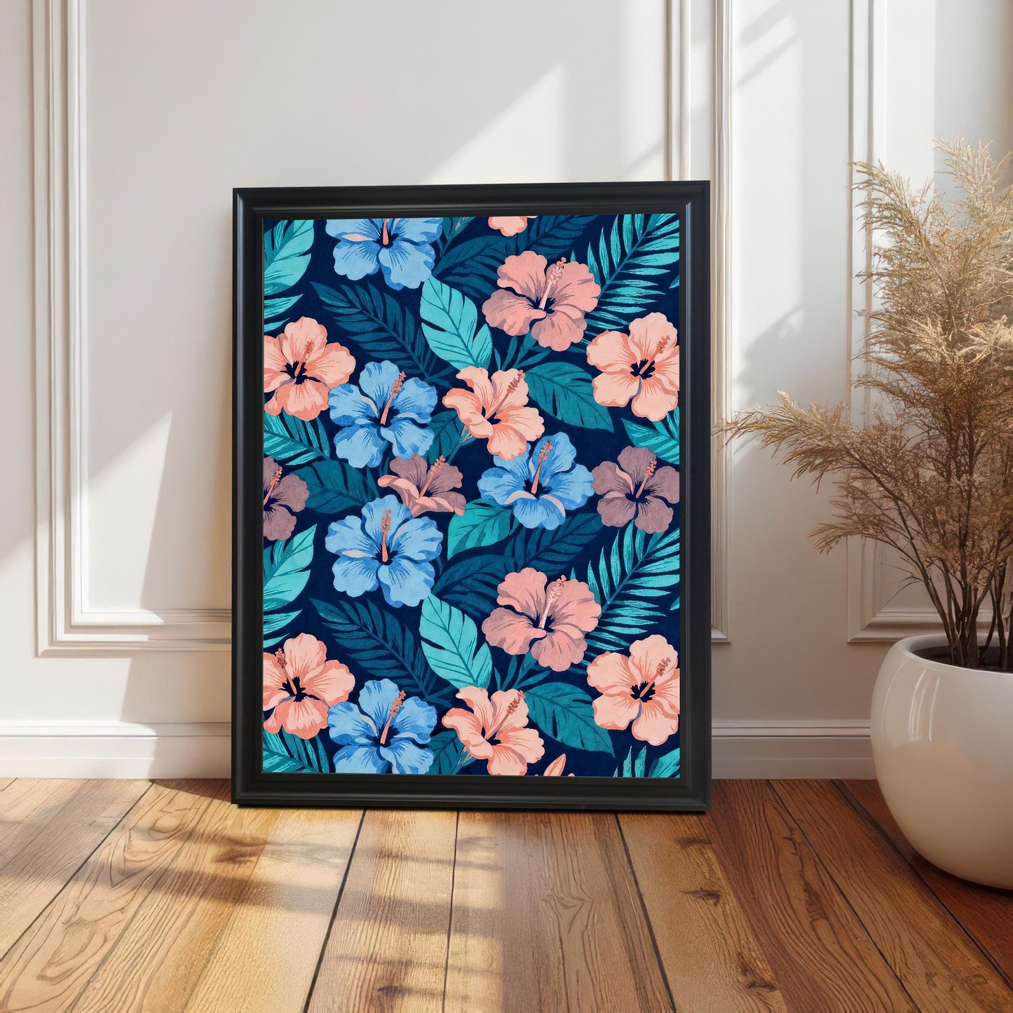 Single framed hibiscus pattern art in a Black frame leaning on a wooden floor against a white paneled wall, next to a potted dried arrangement.