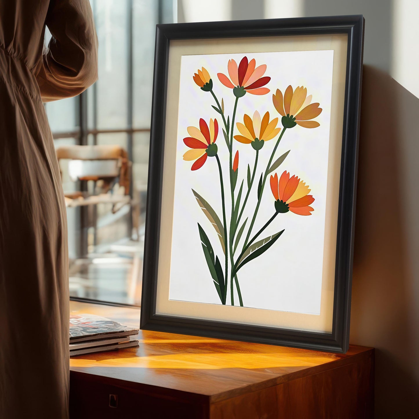 Close-up photo of the framed floral art print in a Black Frame with a Mount, sitting on a wooden cabinet near a window. A person in a light brown dress is partially visible on the left.