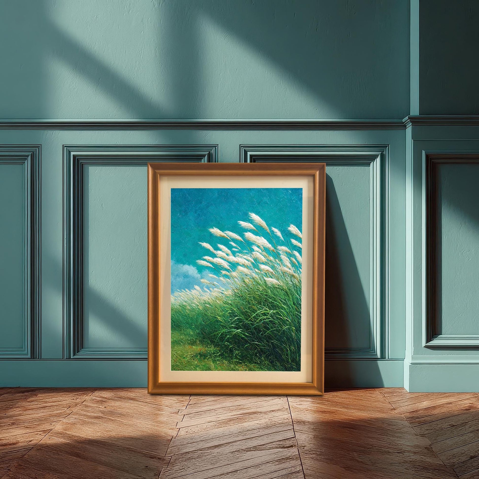 Lifestyle photo showing the framed art print of the windy grass field leaning on a wooden floor against a paneled teal blue wall. The frame is a natural wood color (Orange option).