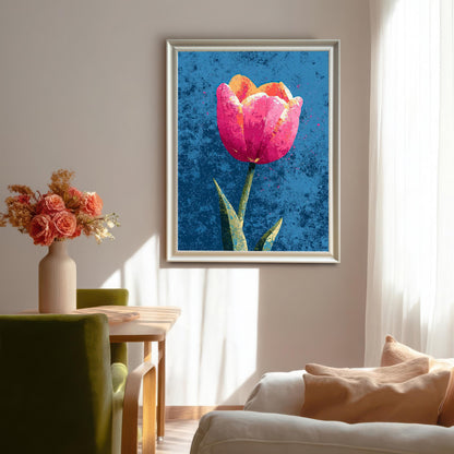 A vibrant, framed art print of a single pink and orange tulip against a distressed blue background, hanging in a sunlit dining room above green chairs and next to a vase of flowers.