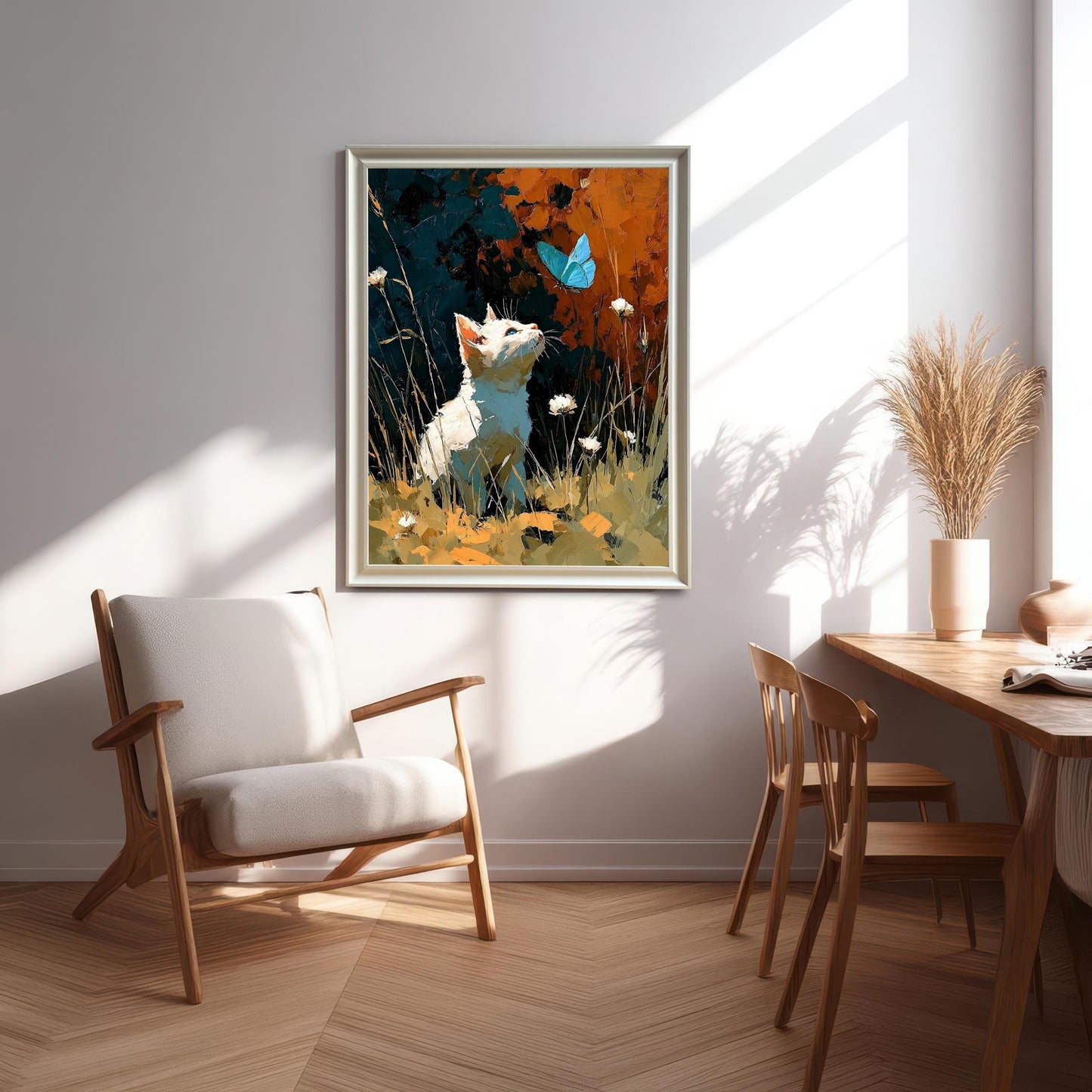 A framed art print of a white cat looking up at a blue butterfly, hanging on a light wall in a sunlit modern dining and sitting area.