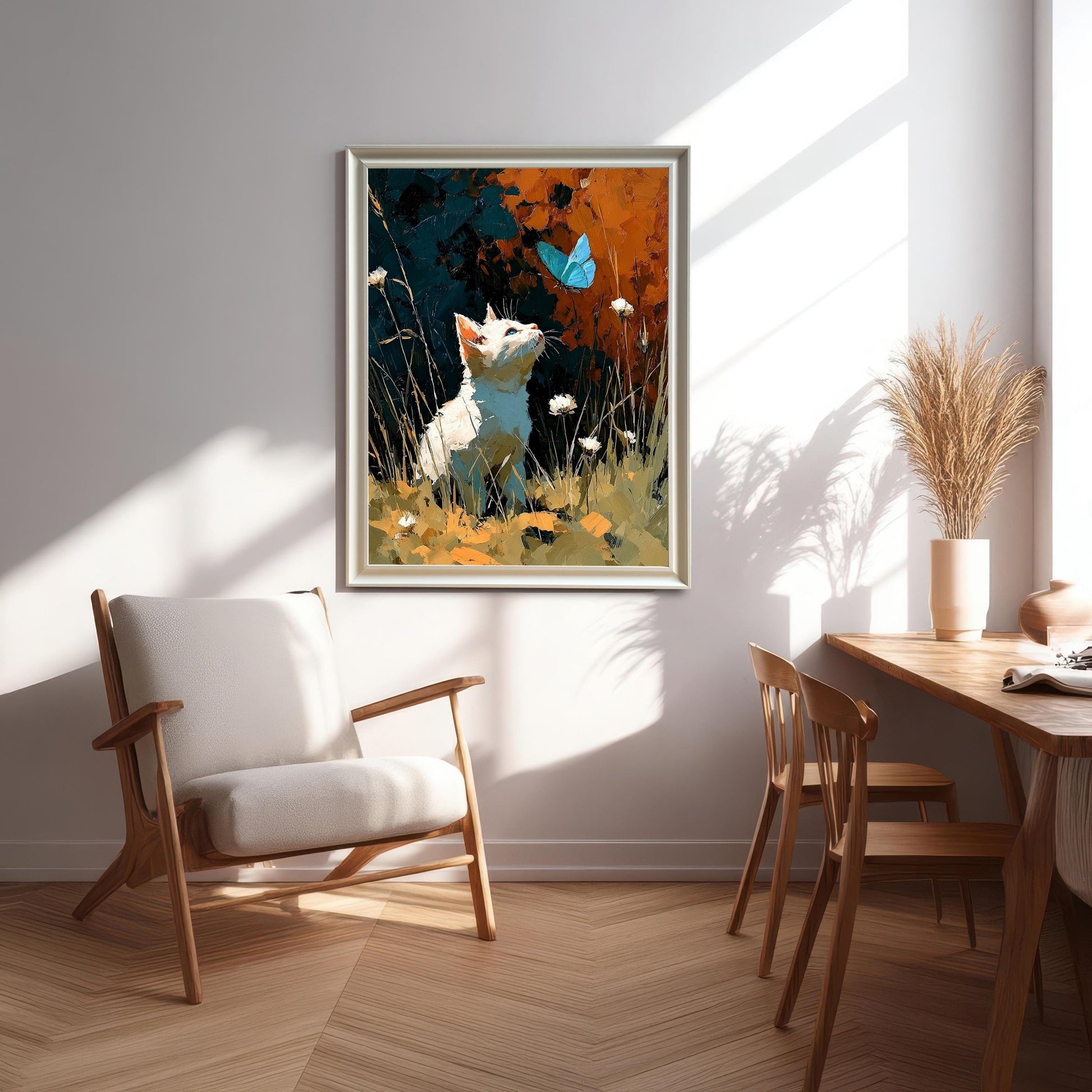 A framed art print of a white cat looking up at a blue butterfly, hanging on a light wall in a sunlit modern dining and sitting area.