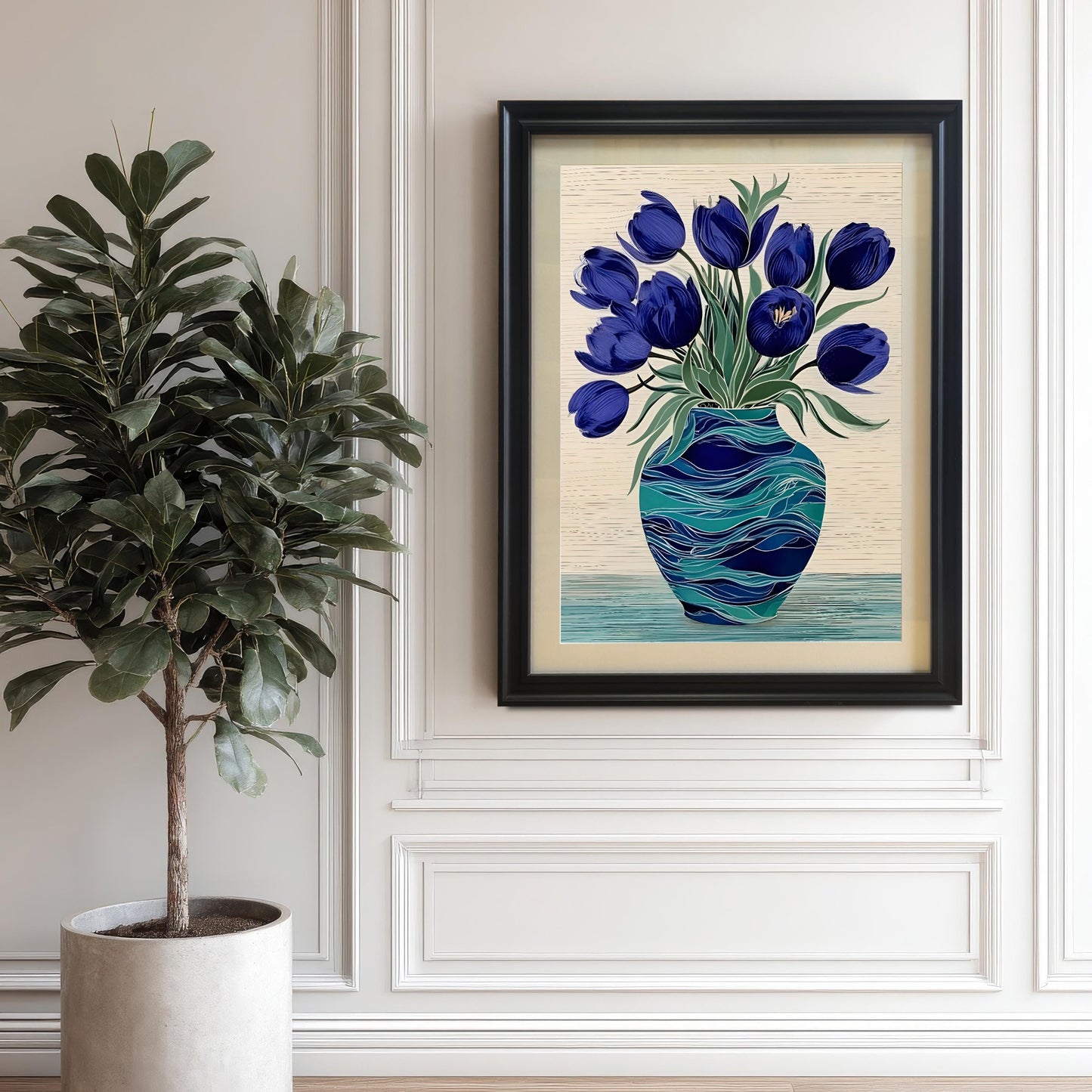 Framed print of deep blue tulips in a swirling teal vase hanging on a white wall with decorative molding, next to a large potted fiddle-leaf fig plant. The frame is Black wood.