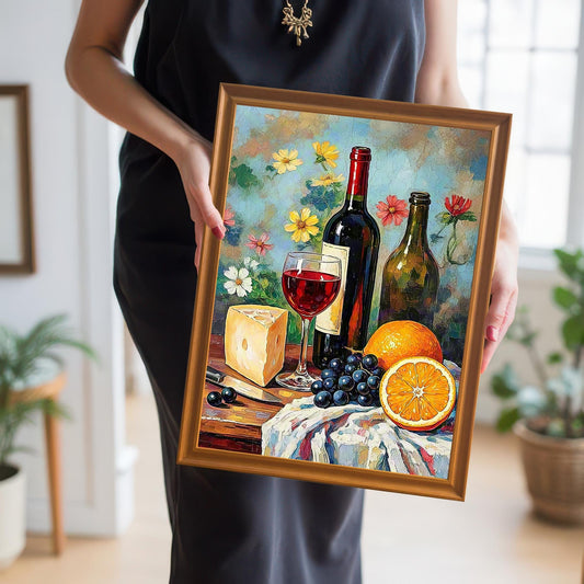 Close-up of a person holding the still life wine and fruit art print in a gold/orange wood frame. The person is wearing a black dress.