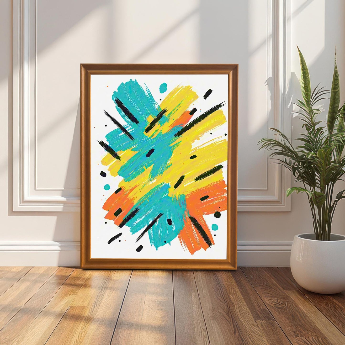 The framed abstract art print in an orange/gold wood frame leaning against a white wainscoting wall, with a snake plant in a white pot beside it.