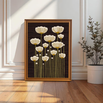 Orange framed art print of abstract white and gold flowers, leaning on the floor against a white paneled wall next to a potted plant.