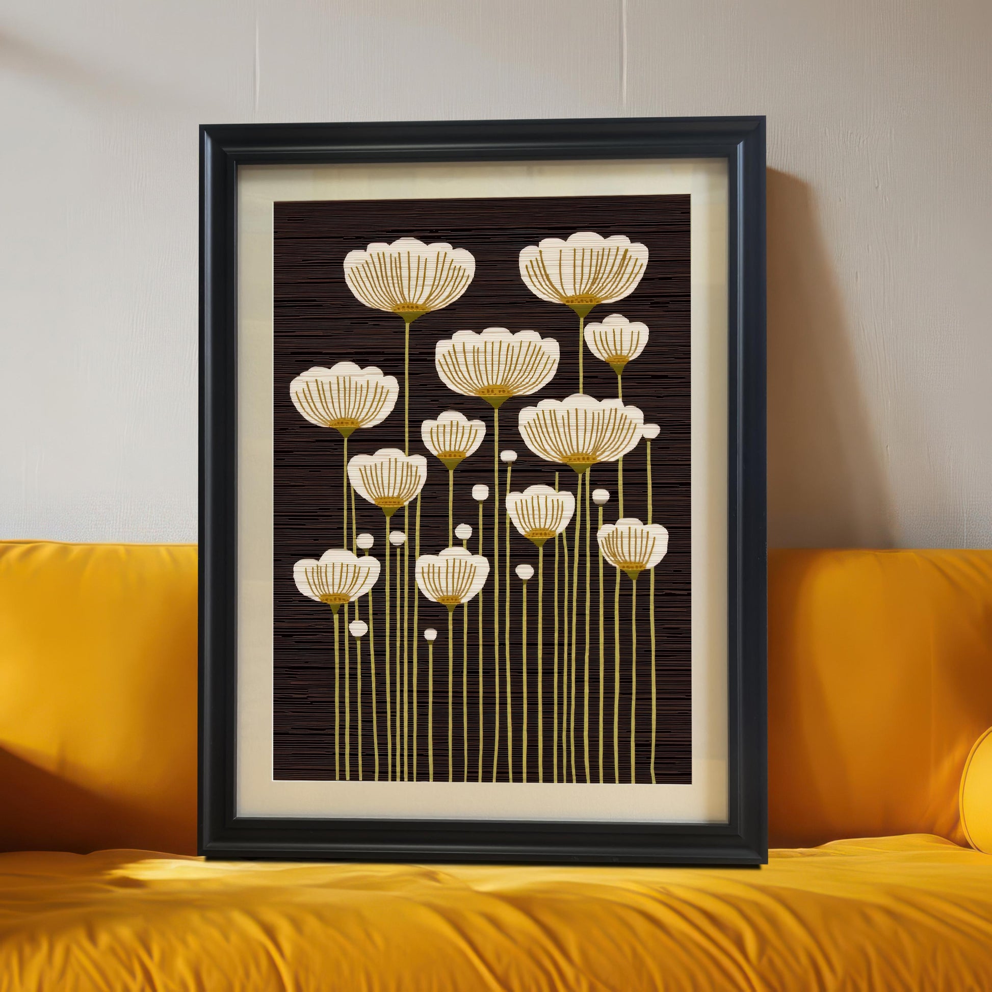 Black framed art print of abstract white and gold flowers, leaning on the floor against a bright yellow couch.