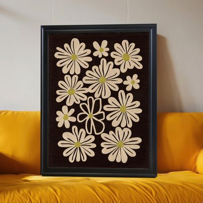 Black framed art print of retro daisy flowers on a dark background, leaning against a wall and resting on a bright yellow sofa.