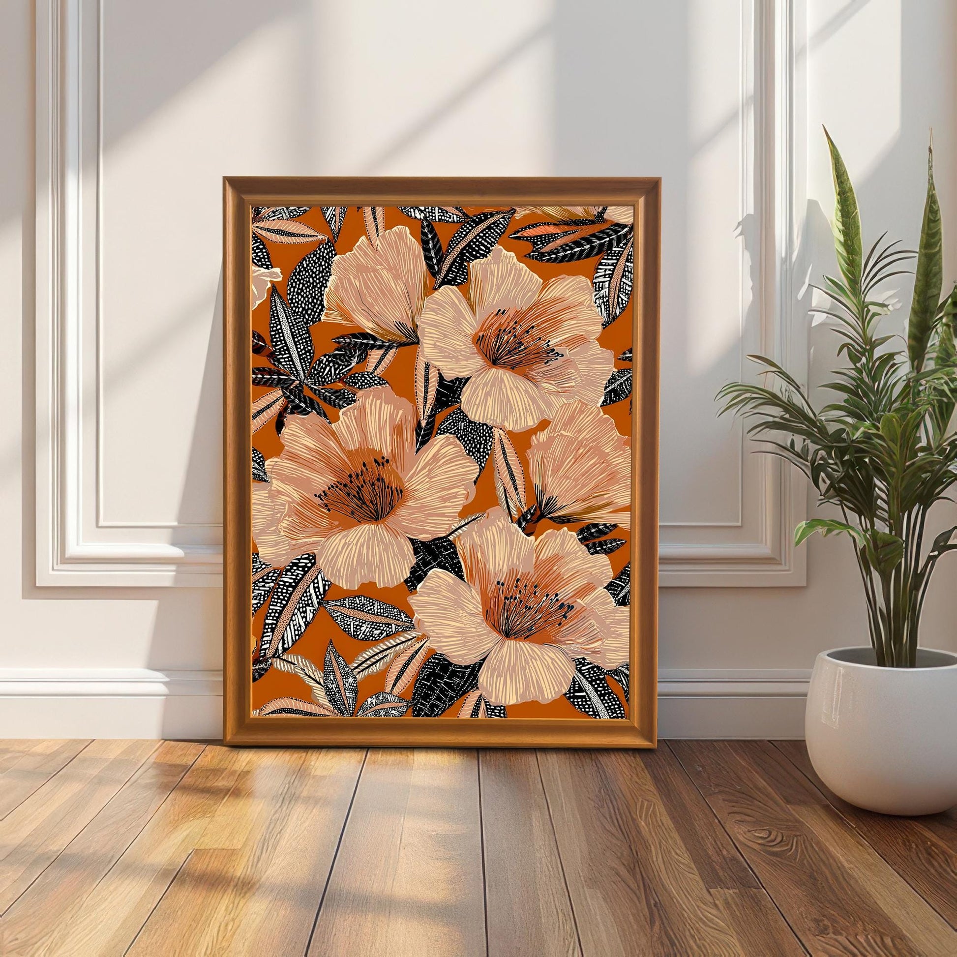 Lifestyle photo of the floral art print in an Orange wood frame leaning on the floor against a white wall with molding next to a tall snake plant.