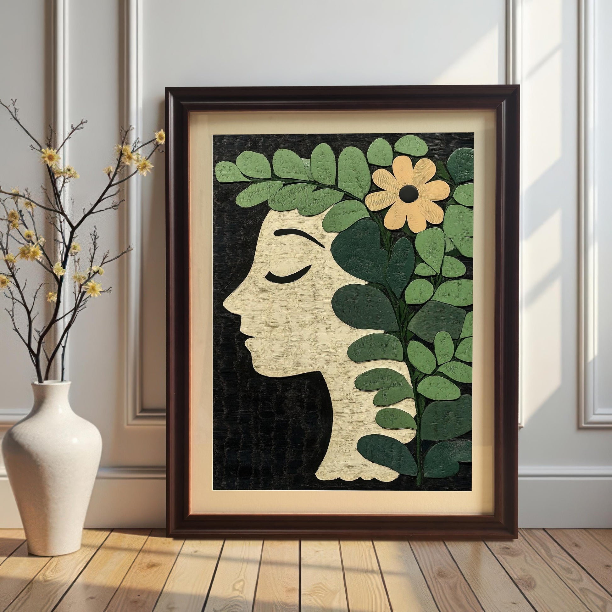 A portrait-oriented botanical profile art print in a Coffee/Dark Brown frame with a mount leaning on a wood floor against a white paneled wall, next to a white vase with decorative yellow branches.