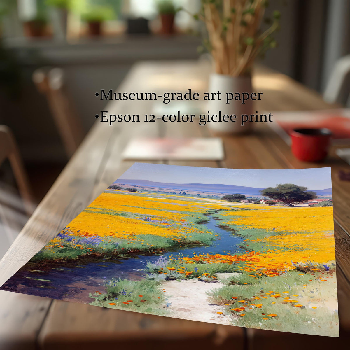 Close-up of an art print, featuring a painting of a yellow and orange poppy field with a stream and path, resting on a wooden table. Text overlays: ""Museum-grade art paper"" and ""Epson 12-color giclee print.""