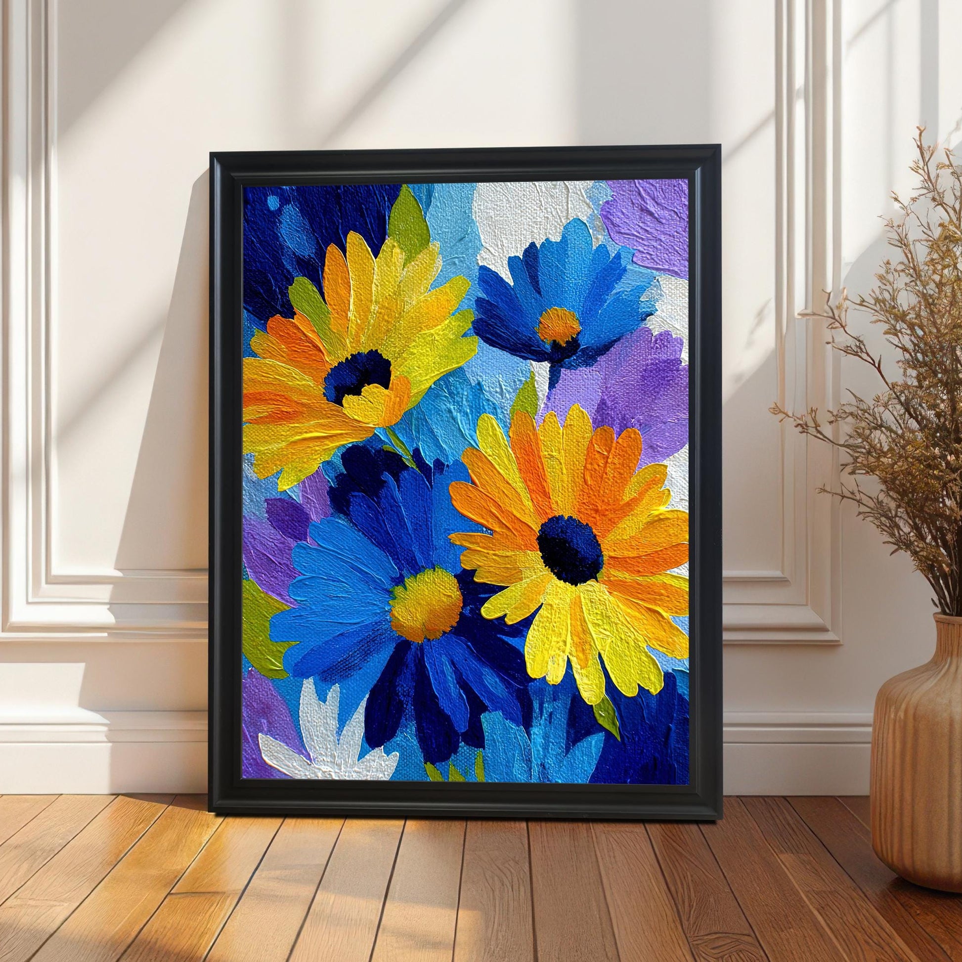 Framed print of the vibrant blue and yellow floral artwork in a black wood frame without a mat/mount, leaning on a wooden floor against a white wainscoted wall with dramatic sunlight and shadows.
