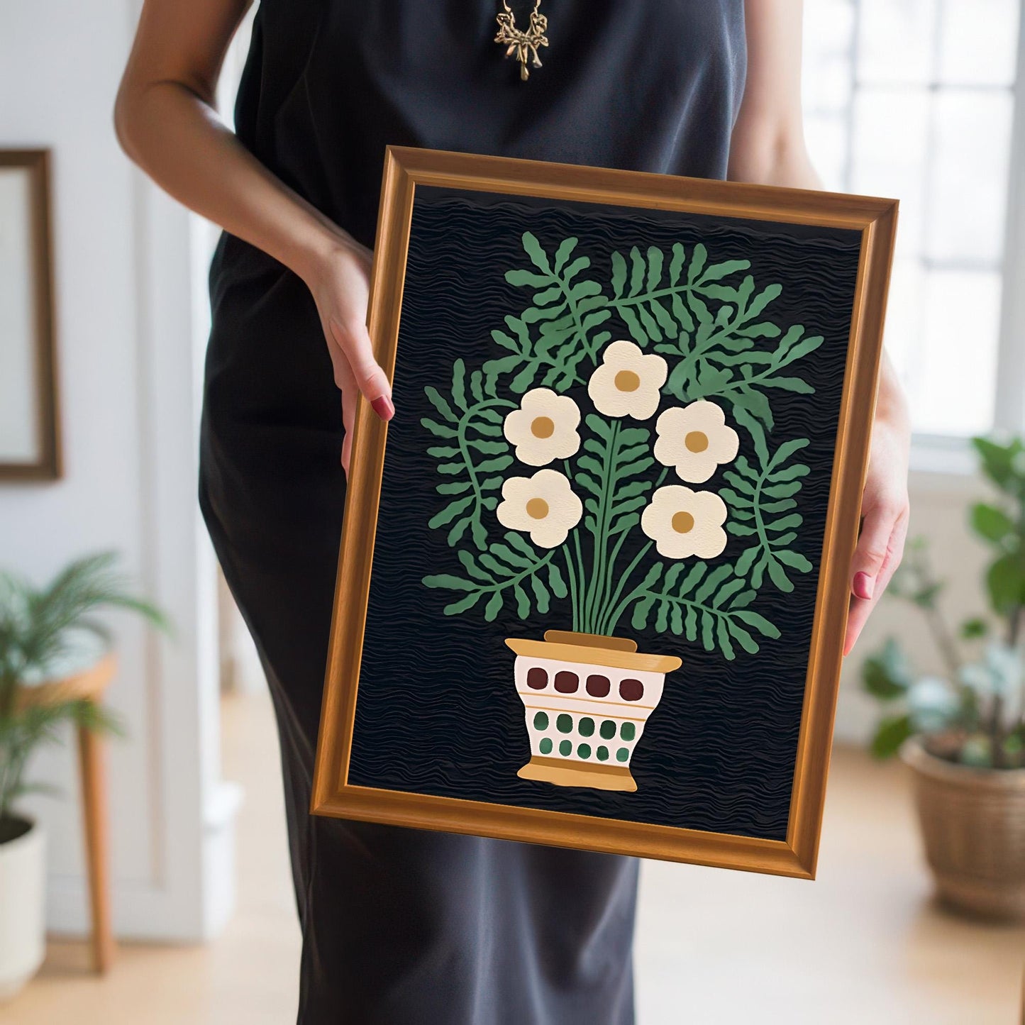 A person in a black dress holds the small framed folk floral print, showcasing the artwork's scale and the warm Orange/Gold frame color.