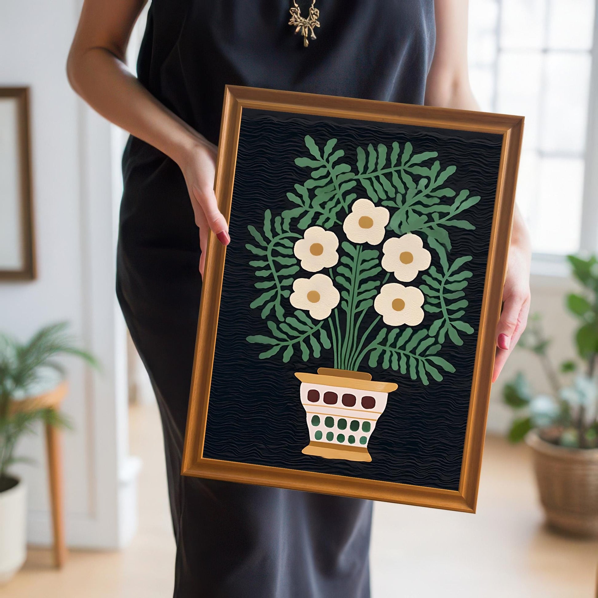 A person in a black dress holds the small framed folk floral print, showcasing the artwork's scale and the warm Orange/Gold frame color.