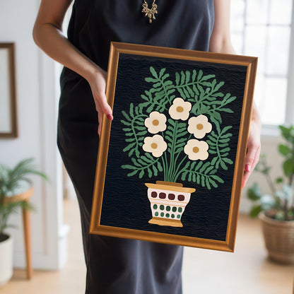 A person in a black dress holds the small framed folk floral print, showcasing the artwork's scale and the warm Orange/Gold frame color.