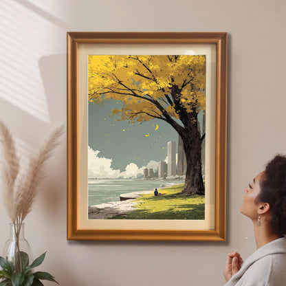 A woman admires the yellow autumn tree and city park art print which is framed in a gold/orange frame with a mount and hanging on a beige wall.