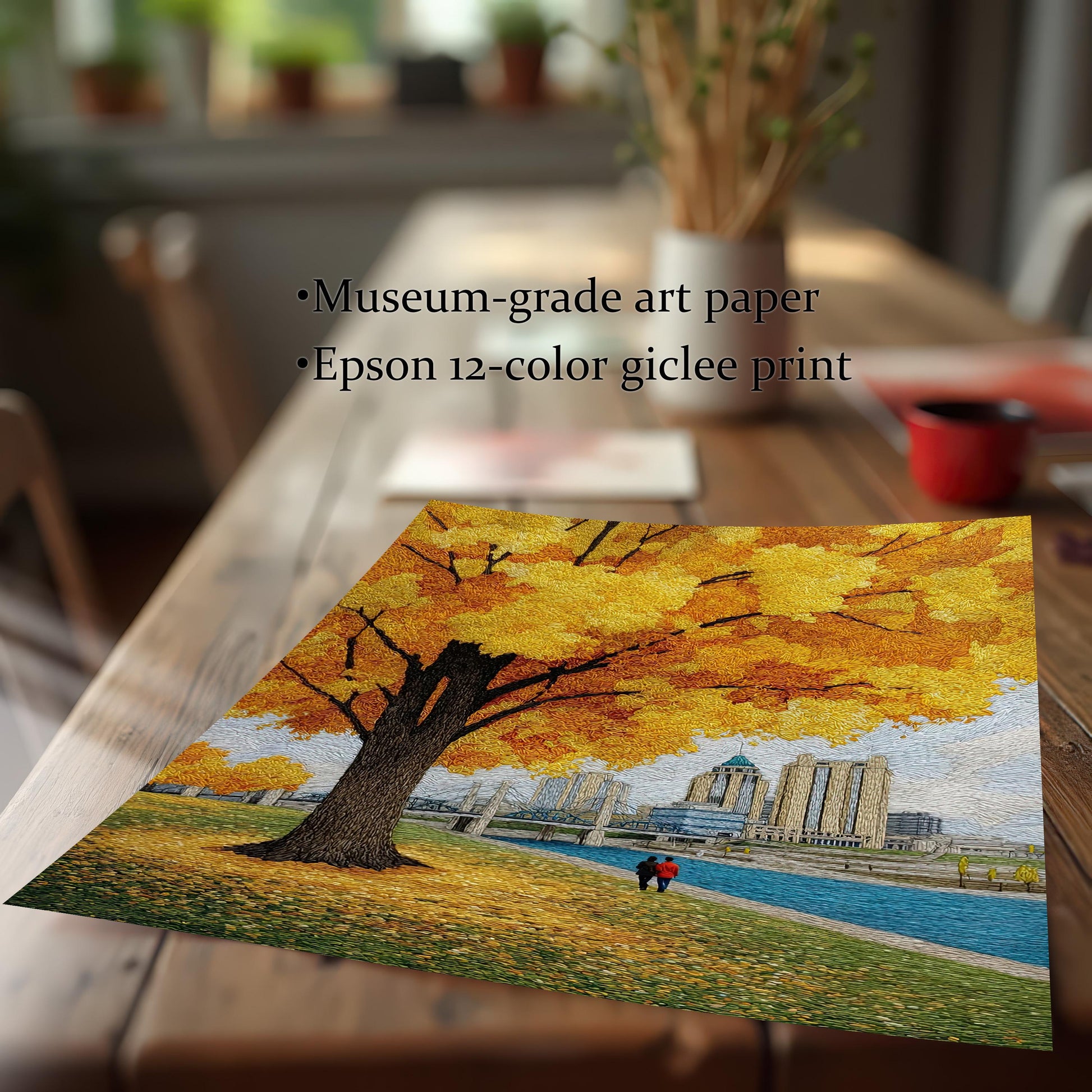 Close-up shot of the unframed art print lying on a wooden table, emphasizing the textured, embroidered look of the yellow leaves and cityscape. Text mentions Museum-grade art paper and Epson 12-color giclee print.