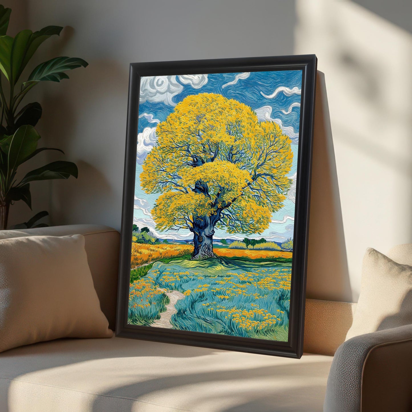 A framed art print featuring a large yellow tree in a field of blue and yellow flowers, displayed in a Black frame and leaning on a light-colored sofa with a large cushion.