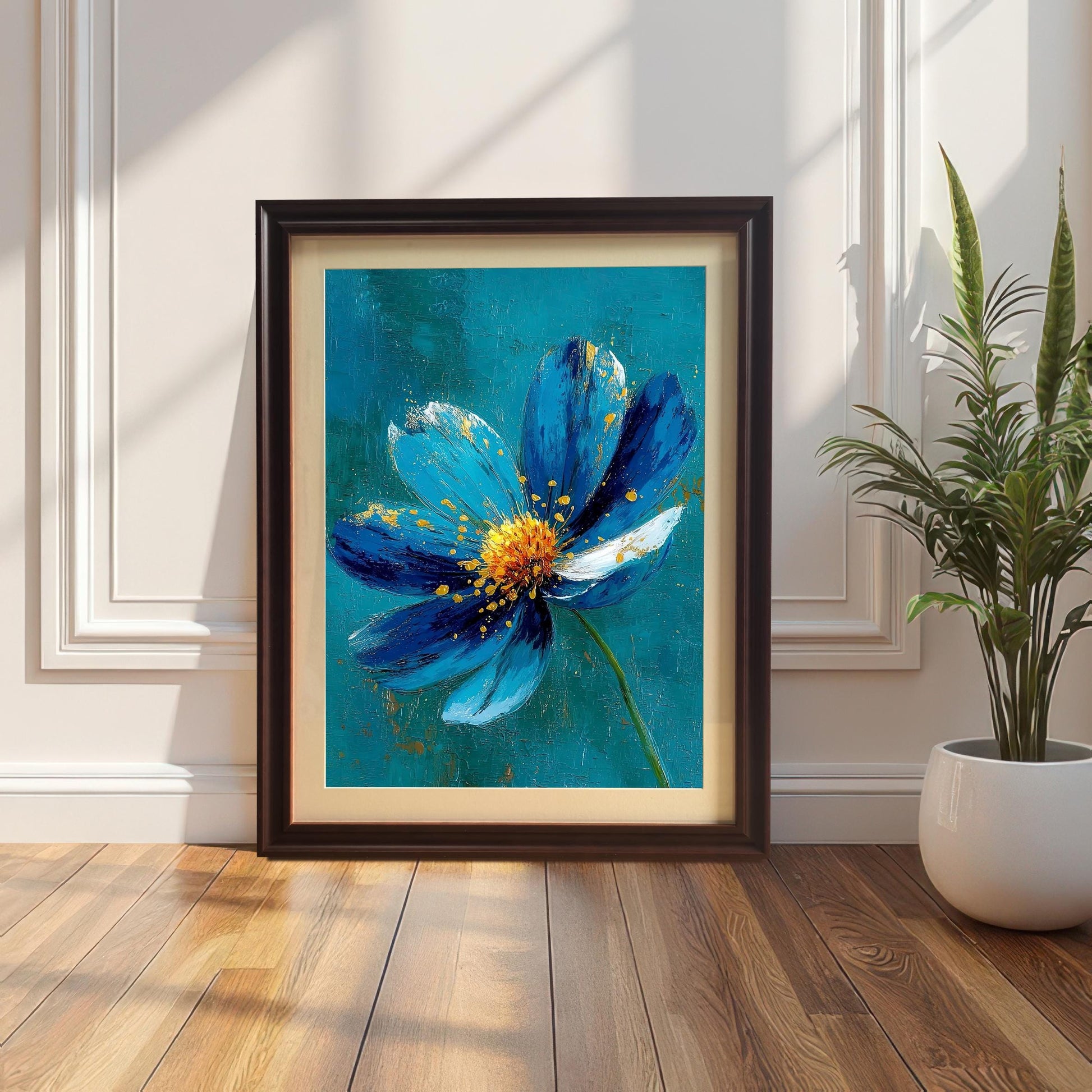 A framed art print of a striking blue flower with gold accents, set in a Coffee-colored frame with a mount (mat). The print is leaning on a wood floor against a white paneled wall next to a houseplant.
