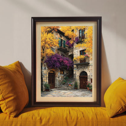Framed art print with a dark brown wood frame resting on a bright yellow couch between two yellow pillows, showcasing the colorful stone building painting.