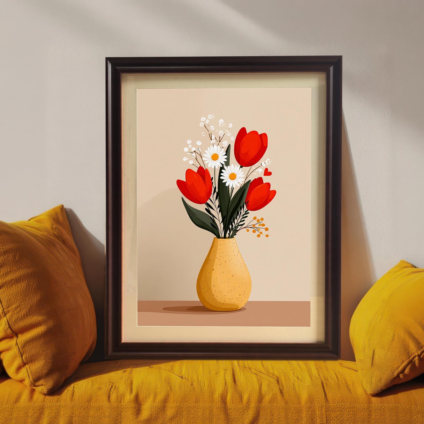 Close-up view of the framed 'Tulips and Daisies in a Yellow Vase' art print. The print is in a Coffee (dark brown/black) wood frame with a mount and rests on a yellow cushion between two pillows.