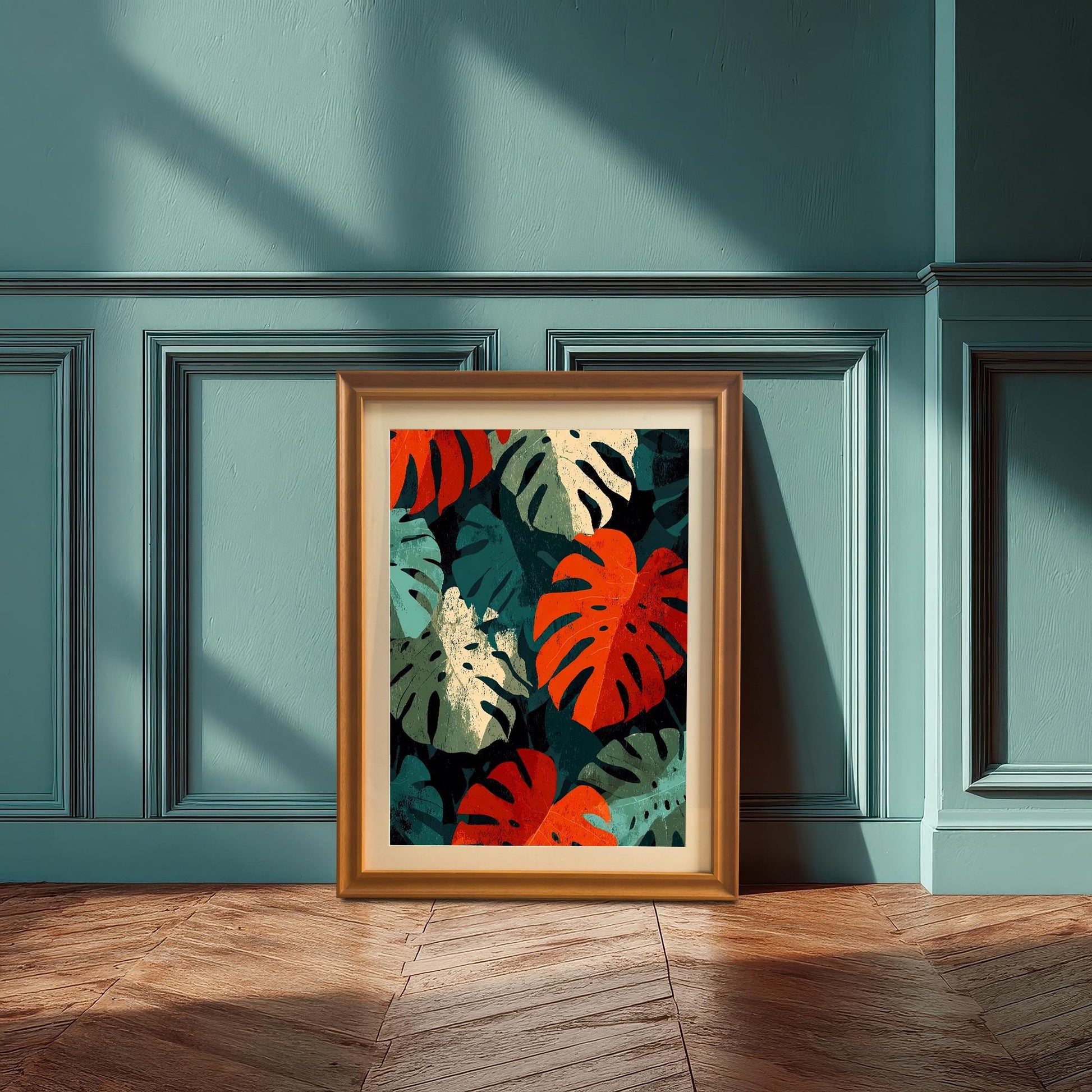 A framed art print of the bold Monstera leaf artwork with an Orange (light brown) wood frame leaning on the floor against a decorative teal-colored wall. This is a lifestyle shot demonstrating the tropical modern decor appeal.