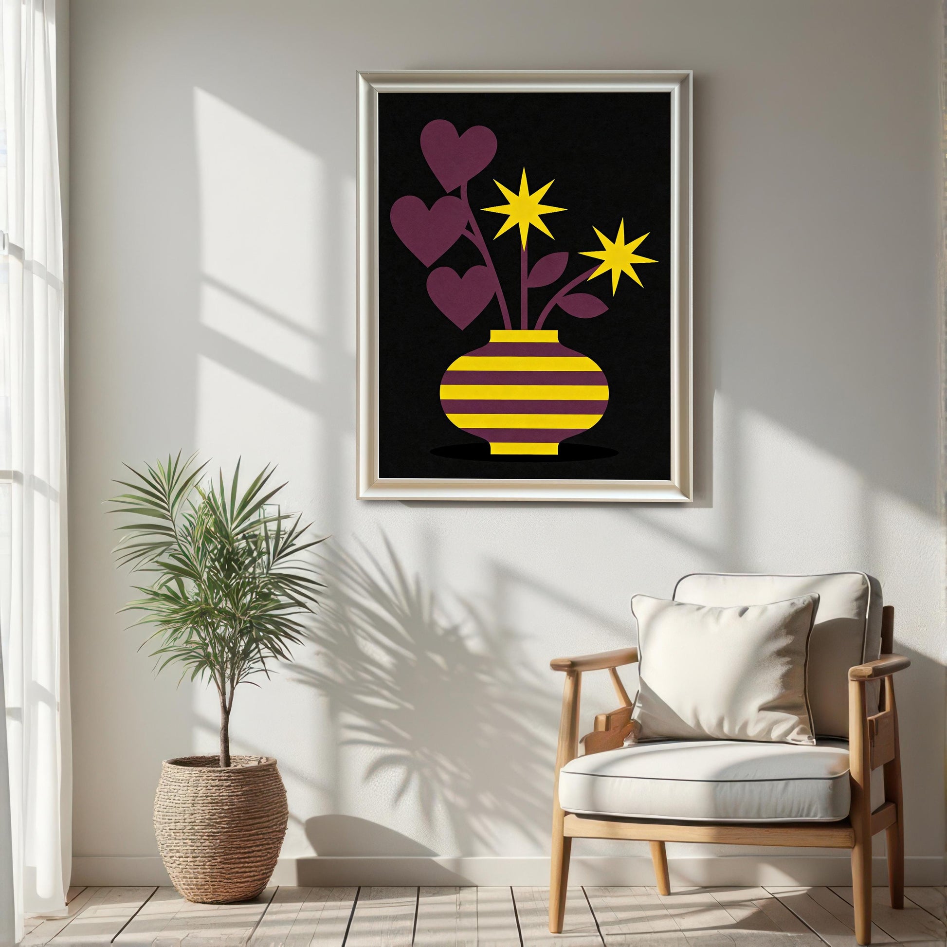 A large White framed art print featuring a yellow and purple striped vase with purple heart-shaped leaves and bright yellow star flowers on a black background. The print is hanging on a white wall in a sunlit room above a light wood chair and next to a potted palm in a woven basket.