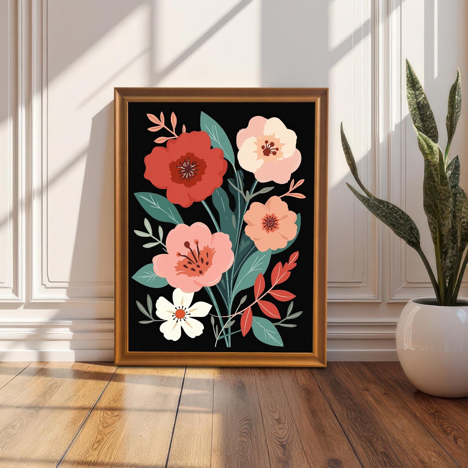 Framed floral art print leaning on a wood floor against a white wall with wainscoting. The frame is a gold/orange wood color, and a snake plant in a white pot is on the right. Natural light casts strong shadows on the wall and floor.