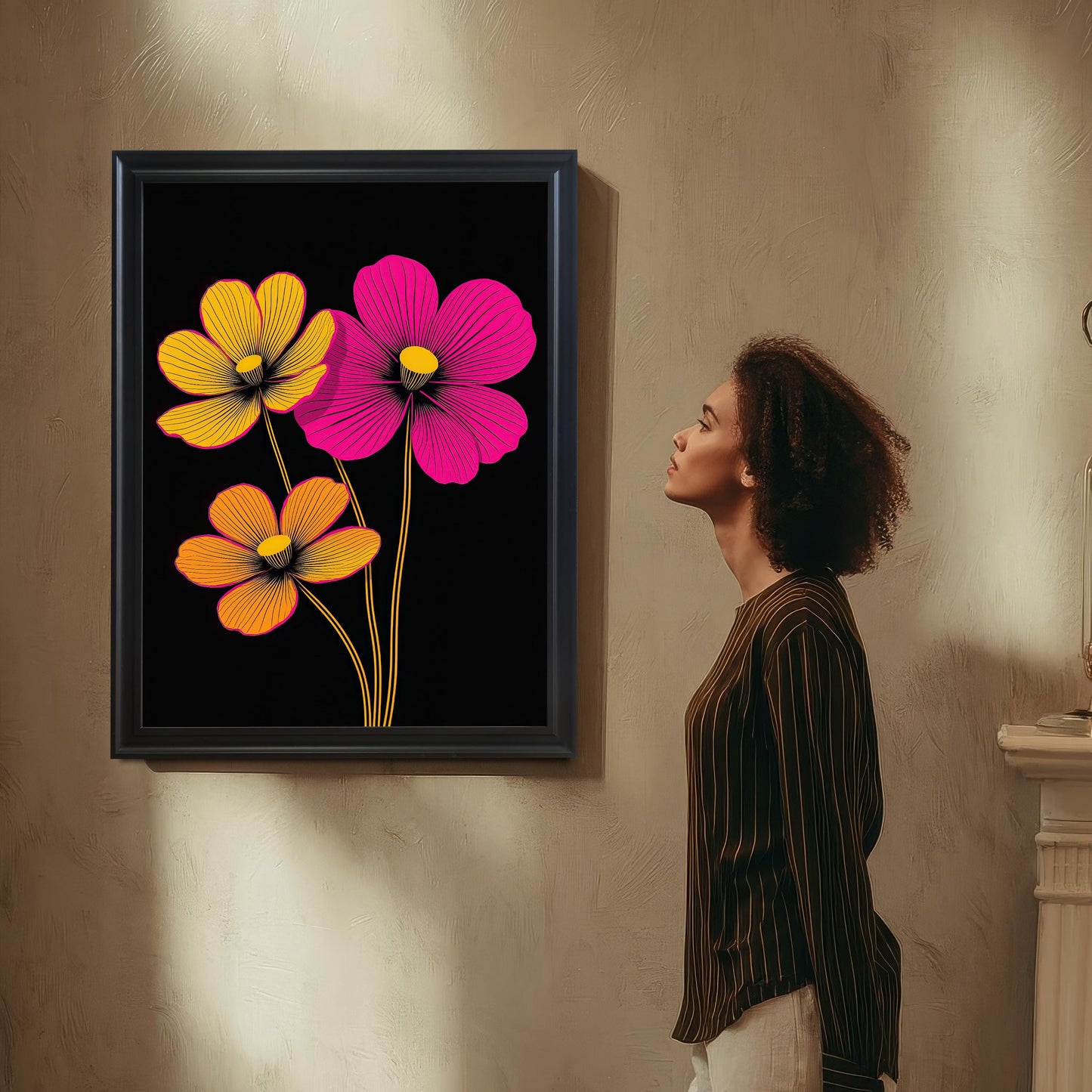Styled image of the Black framed neon floral print hanging on a neutral, textured wall. A woman stands in profile, admiring the modern, high-contrast art with pink and yellow flowers.